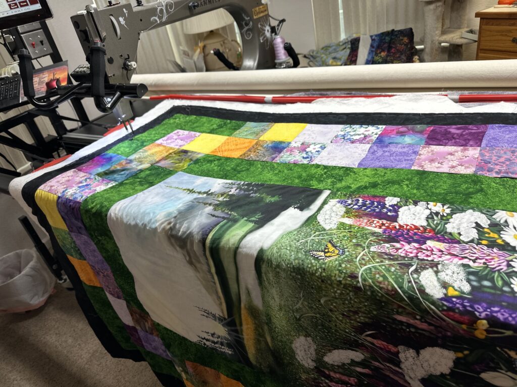 Long Arm quilter showing mountain scene quilt being sewn.
